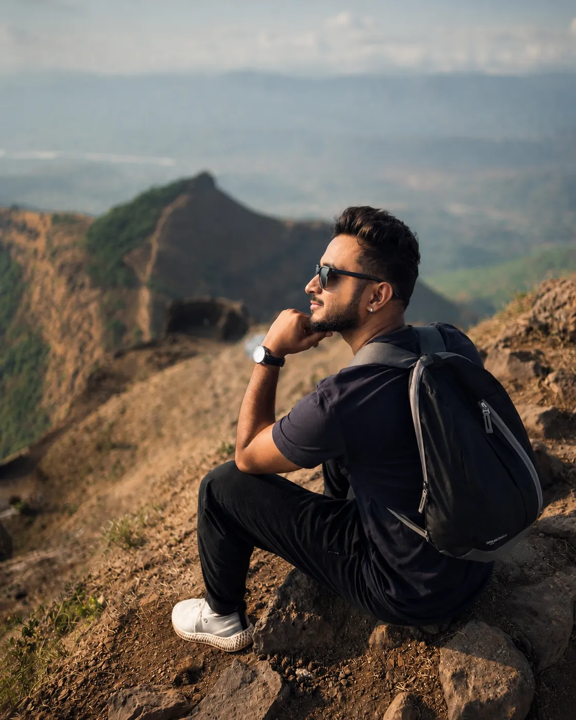 Rutvik sitting on a mountain ridge above a valley